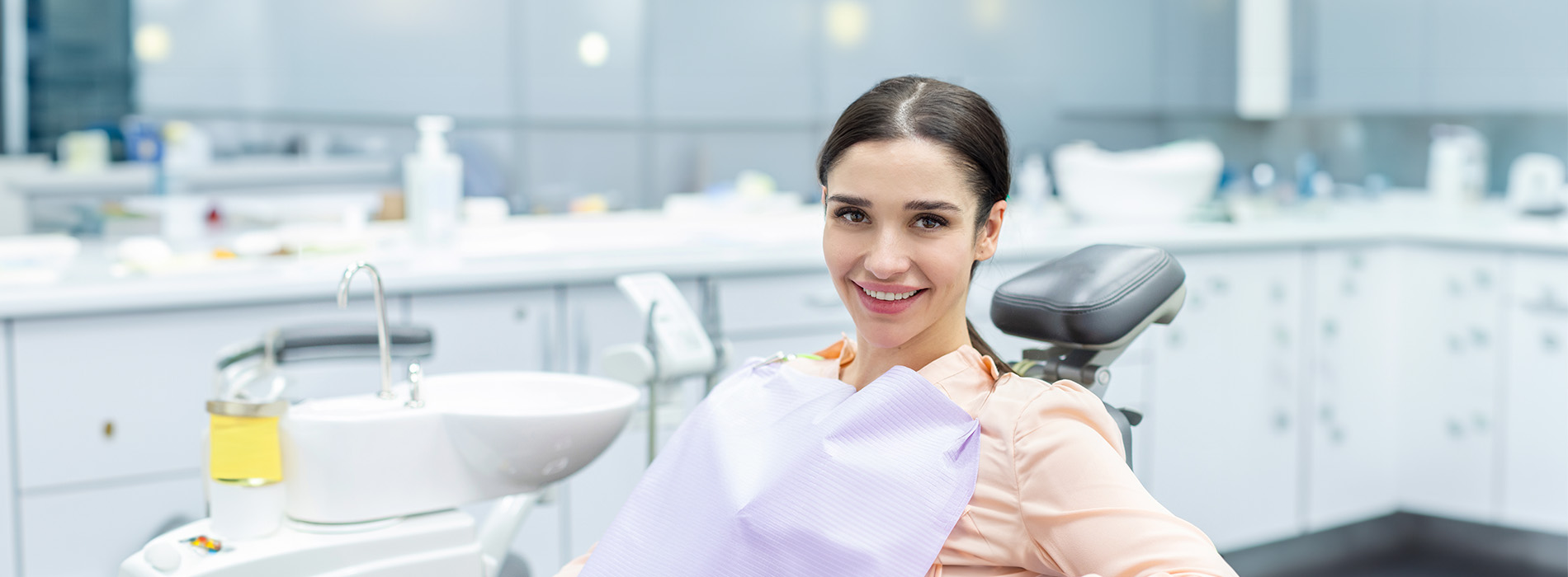 The image shows a group of people, possibly professionals given their attire and the setting that appears to be an office or professional environment. They are gathered around a table with a laptop on it, engaged in what seems to be a discussion or meeting.